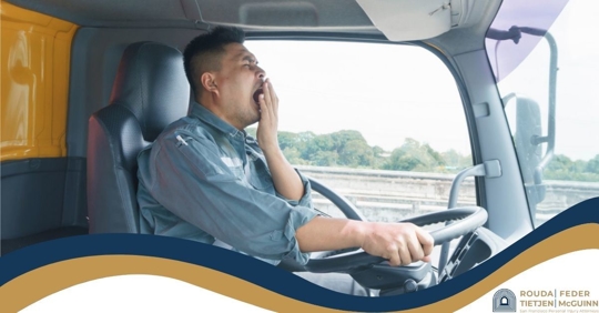 Truck driver yawning with his hand over his mouth.