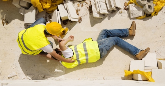 Construction worker tending to another construction worker that is injured.